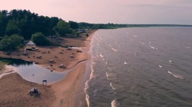 Sakin bir göl manzarası yumuşak kumlu kıyılar, yumuşak dalgalar ve dingin bir öğleden sonra gökyüzü altında yemyeşil..