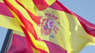 Açık mavi gökyüzü altında İspanya 'nın zengin mirasını ve kültürel kimliğini kutlayan parlak kırmızı ve sarı bayraklar rüzgarda dalgalanıyor..