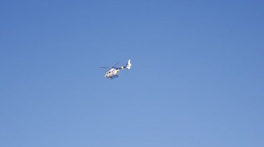 Bir helikopter zarif bir şekilde açık mavi gökyüzünde süzülür. Etrafı sükunet ve sükunetle çevriliyken parlak tasarımını sergiler..