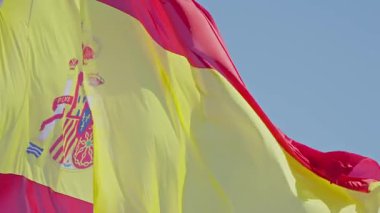 Canlı İspanyol bayrağı, parlak mavi bir gökyüzü altında gururla dalgalanıyor, zengin mirasının ve ulusal gururunun sembollerini sergiliyor..