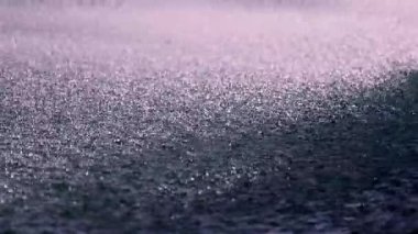 Yumuşak yağmur, sakin bir yüzeye yavaşça düşer. Sönük ışığın altında parıldayan yansımalar yaratır. Huzurlu bir güzellik anını yakalar..