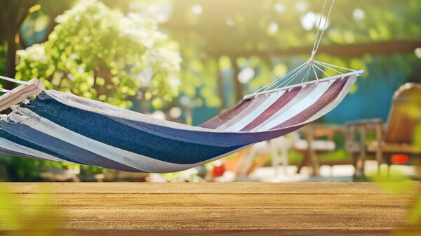 a wood board and hammock on green grass lawn with home backyard, blurred background garden