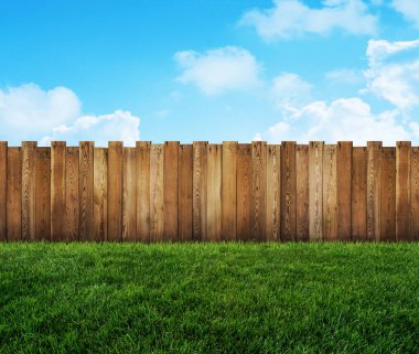 Ahşap bahçe çiti ve arka bahçede yeşil çimen