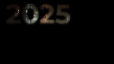 2025 yazısında, parlak renklerle parıldayan, siyah bir arkaplanda beliren. Yeni yılın amacı. Yeni yıl. Mektup, el yazısı. Video sanatı grafikleri