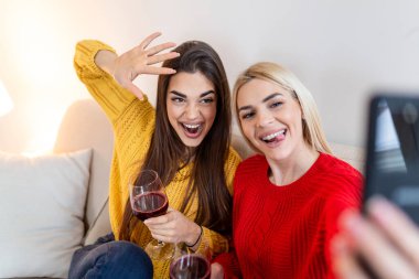 Heyecanlı arkadaşlar selfie çekip gülüyorlar. İki duygusal beyaz kızın kapalı çekimleri. İki yetişkin kadın komik suratlarıyla selfie çekiyor. İki kız arkadaş selfie çekiyor.
