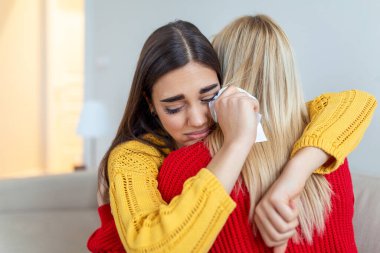 Depresyondaki arkadaşını kucaklayan kadın, yakın çekim. Ağlayan kız arkadaşını destekleyen genç bir kadın. Arkadaşlık teselli ve bakım, boşluğu kopyala