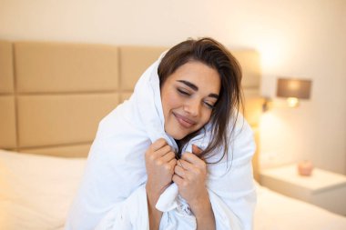 Şefkatini ifade et. Beyaz battaniyeye sarılı bir şekilde yüzünü çeviren sevimli genç bir kadın..