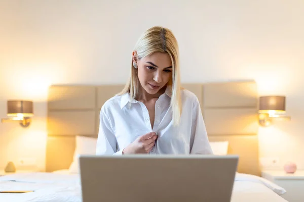 stock image Business woman getting comfortable after work, unbuttoning her shirt and looking at laptop. Businesswoman in hotel room on business trip