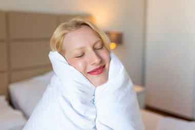 Şefkatini ifade et. Beyaz battaniyeye sarılı bir şekilde yüzünü çeviren sevimli genç bir kadın. Stok fotoğrafı