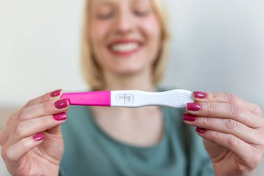 gebelik, doğurganlık, annelik ve insanlar kavramı - mutlu gülümseyen kadın evde gebelik testi seyir