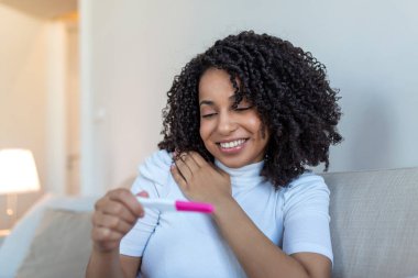Smiling young woman looking on pregnancy test. Happy woman with pregnancy test. Smiling girl telling good news on mobile. Family, child expectation and maternity concept. Copy space