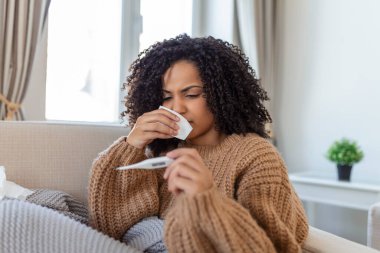 Sickness, seasonal virus problem concept. Woman being sick having flu lying on bed looking at temperature on thermometer. Sick woman lying in bed with high fever. Cold flu coronavirus, covid19