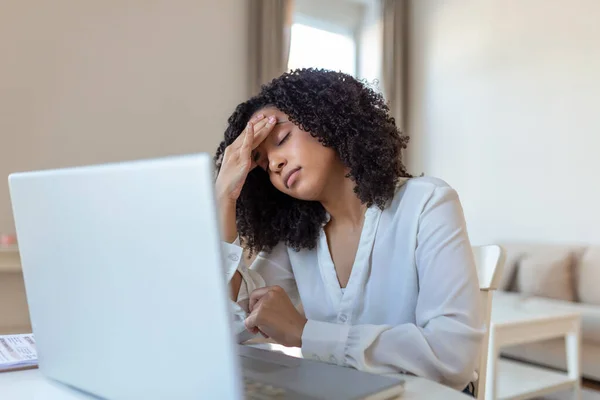 stock image Exhausted businesswoman having a headache in home office. African American creative woman working at office desk feeling tired. Stressed business woman feeling eye pain while overworking