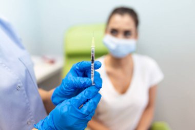Klinikte kadın aşılayan bir pratisyen. Hastanede kadına iğne yapan bir doktor. Hemşire elinde şırınga ve iğne Covid-19 ya da koronavirüs aşısı. Enjeksiyon kovid aşı konsepti..
