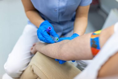 Hemşire, doktor ya da tıp teknisyeninin mavi eldivenli eli hastanedeki bir hastadan kan örneği alıyor..