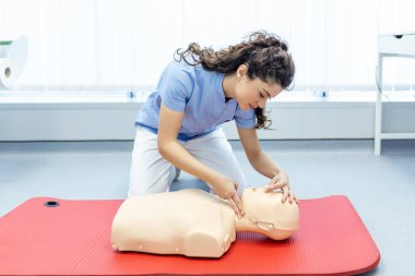 İlk yardım eğitimi sırasında manken üzerinde suni teneffüs tekniği uygulayan kadın. İlk yardım eğitimi, kardiyopulmoner resüsitasyon. Suni teneffüste ilk yardım kursu..