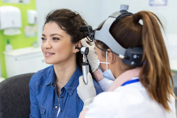 stock image Close up of a female doctor carefully holding the ear of his patient to establish a clearer view of the inside of his ear, to see if he requires hearing aids at a modern clinic