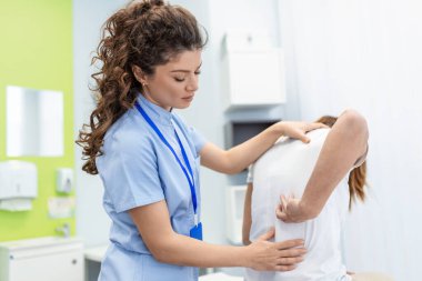 Fizyoterapist kadınlarda tedavi uyguluyor. Sırt ağrısı hastası, tedavi, tıp doktoru, masaj terapisti. Ofis sendromu.