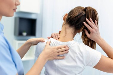 Woman doctor osteopath in medical uniform fixing woman patients shoulder and back joints in manual therapy clinic during visit. Professional osteopath during work with patient concept clipart