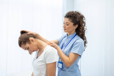 Lisanslı kayropraktik uzmanı ya da klinikteki kadın hastaya boyun masajı yapan manuel terapist. Omurga incinmesi ya da romatolojik sorunu olan genç bir kadın profesyonel doktordan yardım alıyor.