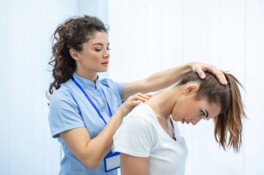 Lisanslı kayropraktik uzmanı ya da klinikteki kadın hastaya boyun masajı yapan manuel terapist. Omurga incinmesi ya da romatolojik sorunu olan genç bir kadın profesyonel doktordan yardım alıyor.