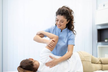 Close up of female osteopath doing shoulder blade therapy on young woman. clipart