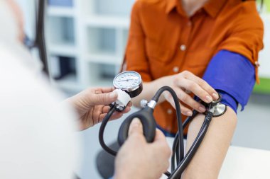 Steteskopla sfenometre kullanan bir doktor hastanede kan basıncını ölçüyor..