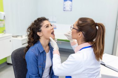 Depresifli doktor boğaz ağrısını kontrol ediyor. Deneyimli doktor yetişkin kadınlarda boğaz ağrısı olup olmadığını kontrol ediyor.