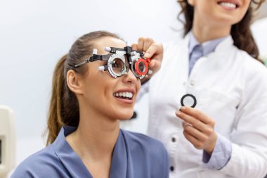 Optometrist deneme çerçevesi ile kadın muayene Oftalmolog. kadın hasta Oftalmolojik klinikte vizyonu kontrol etmek.