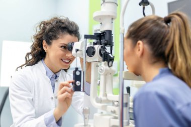 Modern klinikteki muayenede kadın hastayla göz doktoru. Oftalmolog göz sağlığını korumak ve iyileştirmek için özel tıbbi ekipmanlar kullanıyor..