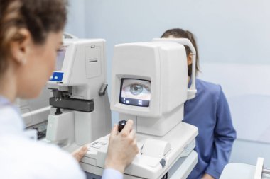 Modern klinikte özel optik cihazlarla gözleri test eden bir doktor. Oftalmolojist, göz hekimliği ofisinde yapılan tıbbi muayene sırasında dijital mikroskop kullanan bir hastanın gözlerini inceliyor.