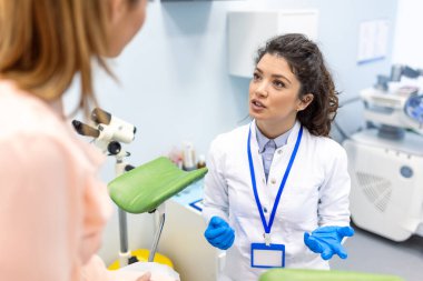 Modern klinikteki tıbbi danışmanlık sırasında genç bir kadın hastayla konuşan jinekolog. Jinekoloji muayenehanesinde jinekologla birlikte olan hasta.