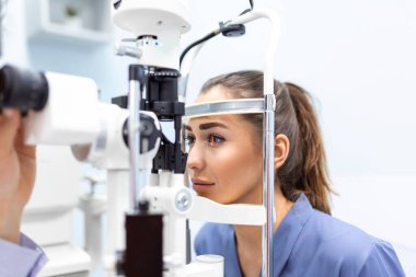 Optometrist, göz hekimliği kliniğindeki yarık lamba üzerinde kadın hastayı muayene ediyor. Genç ve güzel bir kadına özel göz tansiyonu teşhisi konur..