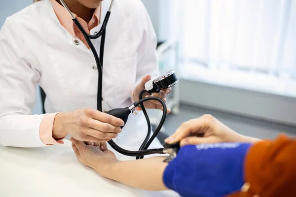 血圧の測定 若い女性は現代の診療所で女性医師と面会している 血圧の測定 圧力計 高血圧と高心拍数 — ストック写真