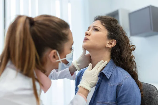 medicine, healthcare and medical exam concept - doctor or nurse checking patient\'s tonsils at hospital. Endocrinologist examining throat of young woman in clinic