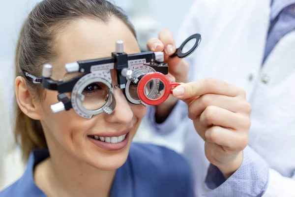 眼科医は 眼科医の試験フレームで女性を検査します 眼科クリニックで視力をチェックする女性患者 — ストック写真