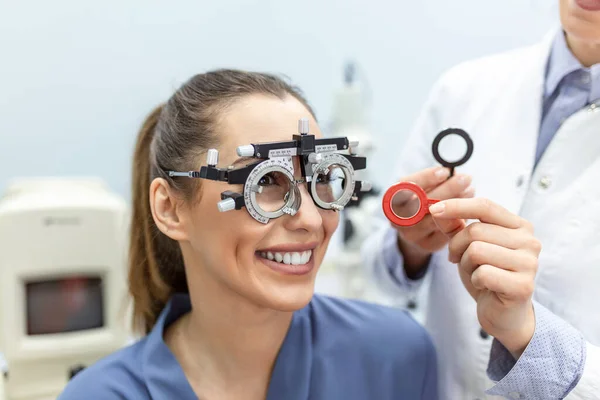 眼科医は 眼科医の試験フレームで女性を検査します 眼科クリニックで視力をチェックする女性患者 — ストック写真