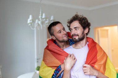 Sevecen erkek eşcinsel çift içeride. Evinde erkek arkadaşına arkadan sarılan bir adam. Gurur ayını kutlayan eşcinsel çift