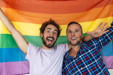 İki genç eşcinsel aşık birbirine sevgiyle bakıyor. Gurur bayrağına karşı birlikte duran iki genç erkek aşık. Sevecen genç eşcinsel çift romantik bir anı paylaşıyor..