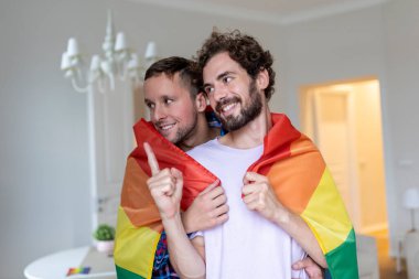Sevecen erkek eşcinsel çift içeride. Evinde erkek arkadaşına arkadan sarılan bir adam. Gurur ayını kutlayan eşcinsel çift