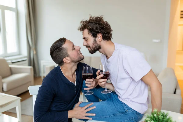 Lgbtq 부부는 서로를 포옹하고 실내에서 와인을 마신다 로맨틱 거실에 서로를바라보고 — 스톡 사진