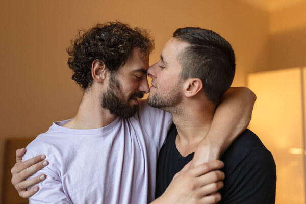Two young man lgbtq gay couple dating in love hugging enjoying intimate tender sensual moment together kissing with eyes closed