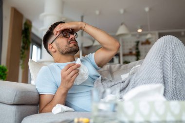 Covid-19 semptomlarından muzdarip bir adam evde yatarken yüksek ateş ve öksürük normal bir hayat yaşamasını engelliyor. Kendini izole ediyor olmalı. Evde kal.