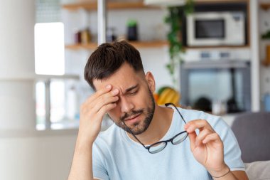 Uzun çalışmadan sonra gözlüğünü tutan yorgun gözlü bir adam.