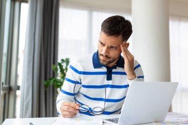 Genç işadamı ofiste çalışıyor. Başı ağrıyor. Baş ağrısı konsepti ofis sendromu olan bir adam.