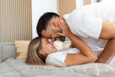Yatakta öpüşen güzel bir çift. Güzel genç bir çift yatakta birlikte yatıyor..