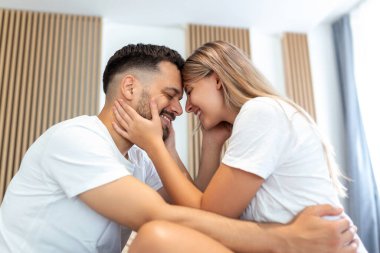 Evdeki güzel genç çift. Sarılmak, öpüşmek ve birlikte vakit geçirmekten zevk almak. Yatak odasındaki tutkulu güzel çift ön sevişmenin tadını çıkarıyor.