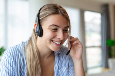 Ofiste bilgisayarla çalışan kulaklıklı bir iş kadını. Ofiste çalışan müşteri hizmetleri asistanı. Telemarketing müşteri hizmetlerinde kulaklıklarla ve laptopla çalışan kadın operatör..