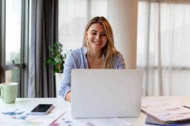 Güzel kadın serbest yazar dizüstü bilgisayarla uzaktan kumandayı planlama projesi için bilgi topluyor. Modern dizüstü bilgisayarda e-posta okuyan kadın