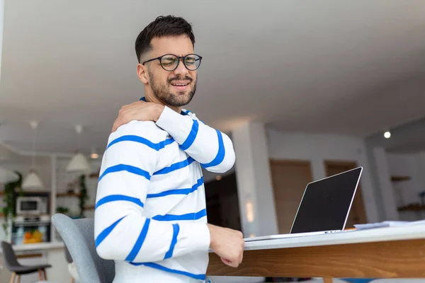 Young businessman overtime work and feel shoulder pain while using laptop computer at home